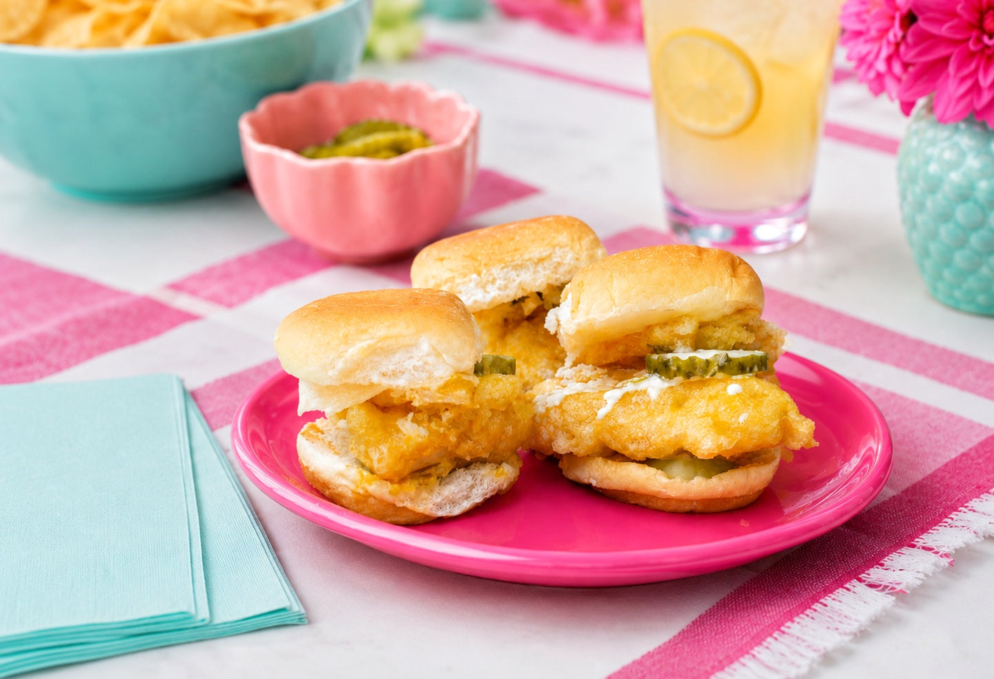 Buffalo ranch chicken tempura sliders on a pink plate with pickles and lemonade