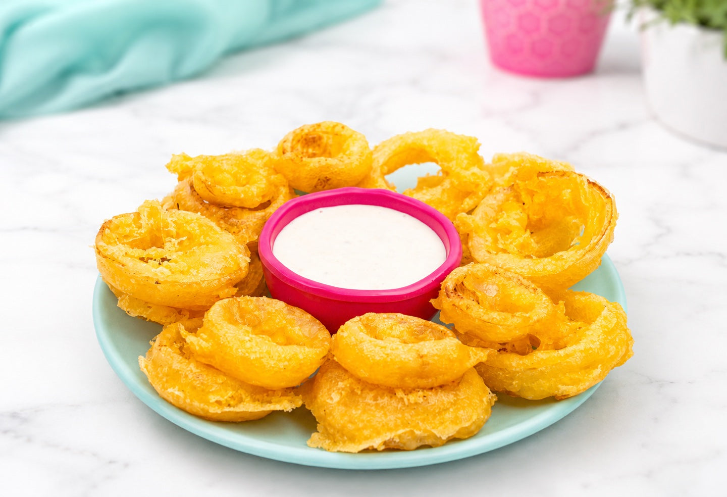 Golden tempura onion rings arranged around a creamy ranch dip