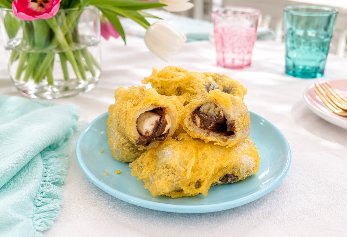 Crispy tempura chocolate banana rice paper rolls cut open on a blue plate.